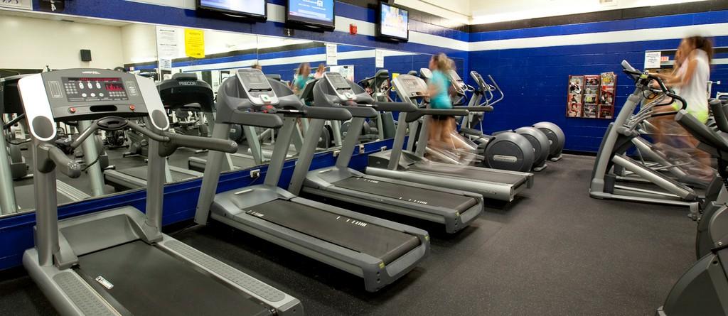 a row of treadills in the university fitness center with a student running on one