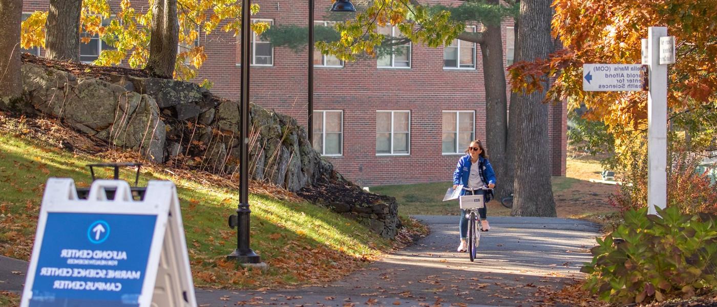 秋天，一名学生骑着自行车穿过比德福德校园