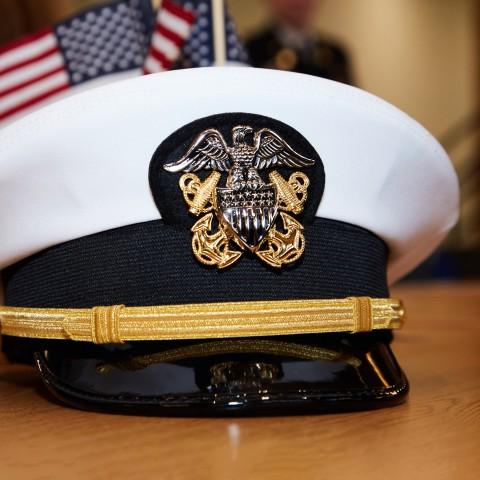 A military captain's hat with American flags in the background